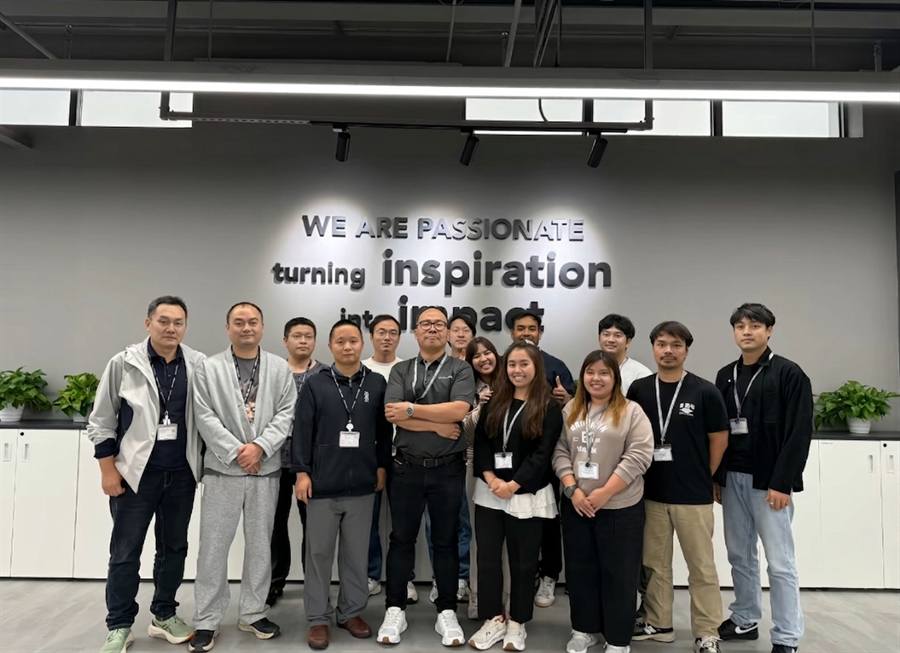 Shenzhen Huodian Electronic Technology team group photo — our sales, engineering, QA and warehouse members in front of the 'We Are Passionate · Turning Inspiration Into Impact' company slogan at our Shenzhen Huaqiangbei office.
